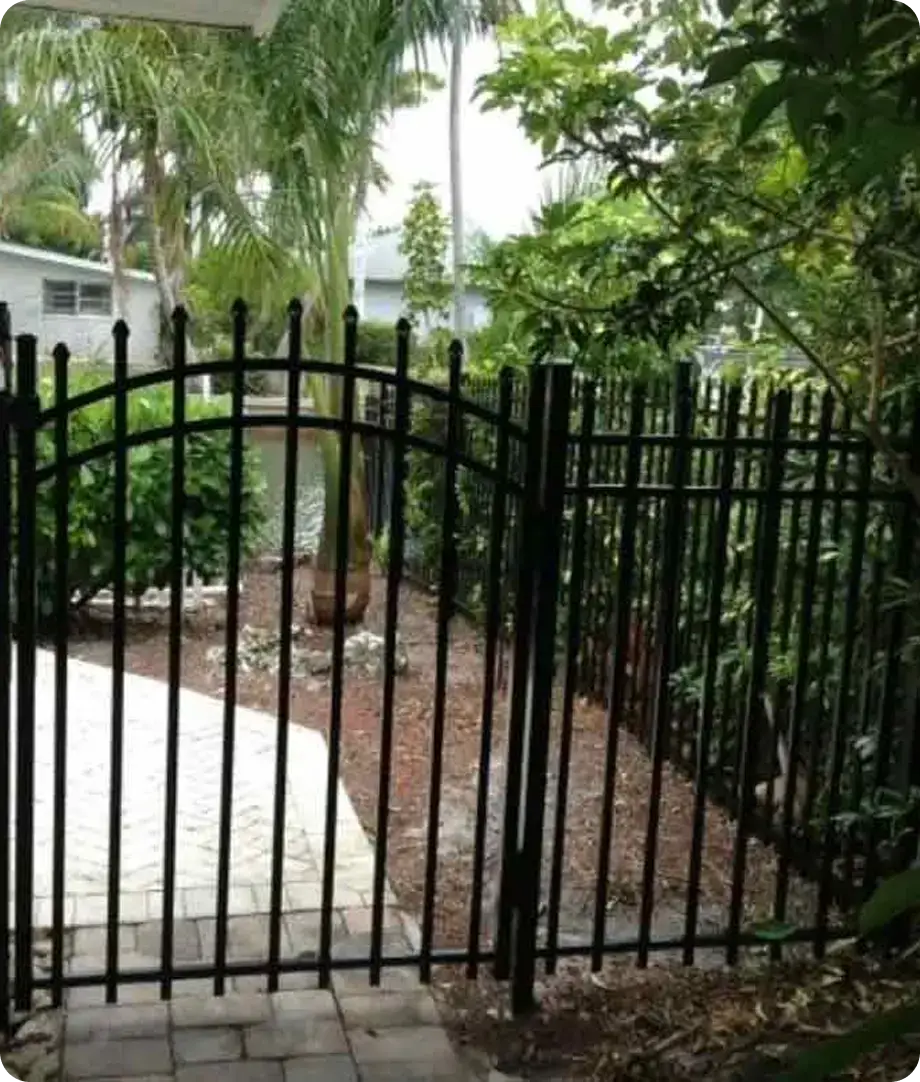 Black aluminum arched walk gate on a garden path by Premier Fence of SWFL