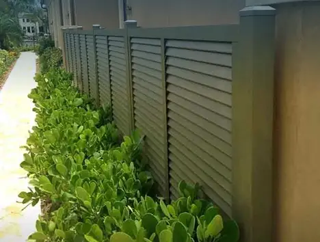 Louvered privacy fence above a hedge line by Premier Fence of SWFL